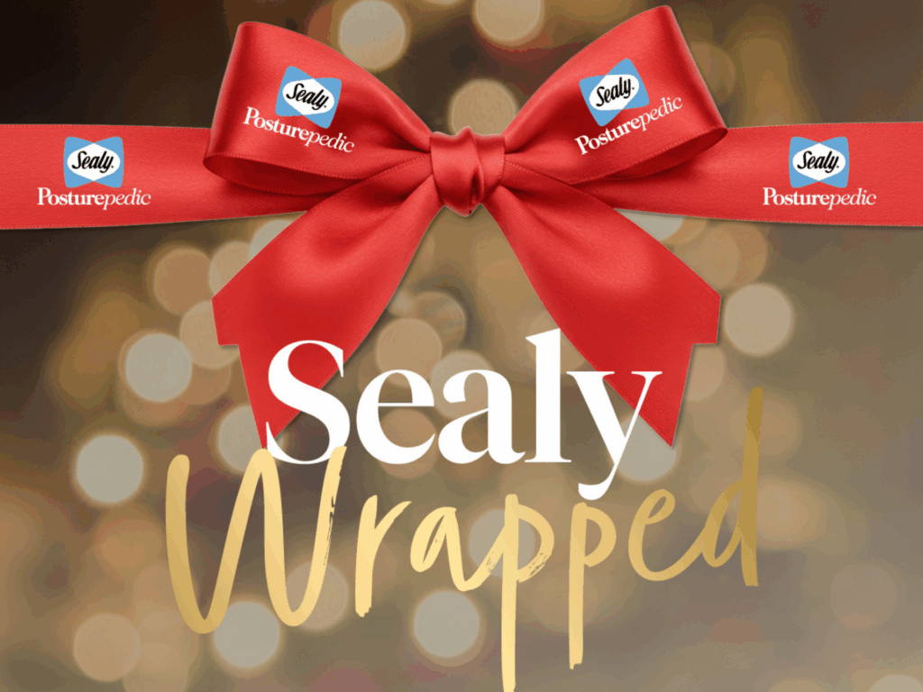 A luxury festive visual with a red satin ribbon bow featuring Sealy Posturepedic branding, over a warm, blurred holiday backdrop, highlighting the title “Sealy Wrapped” in elegant white and gold typography.