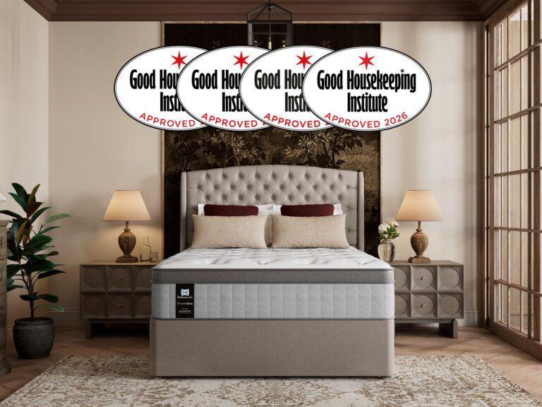 A Sealy Posturepedic Elevate Ultra mattress styled in a luxury bedroom, shown with a tufted upholstered headboard and neutral bedding. A banner highlights that the mattress is award-winning for four consecutive years and approved by the Good Housekeeping Institute.